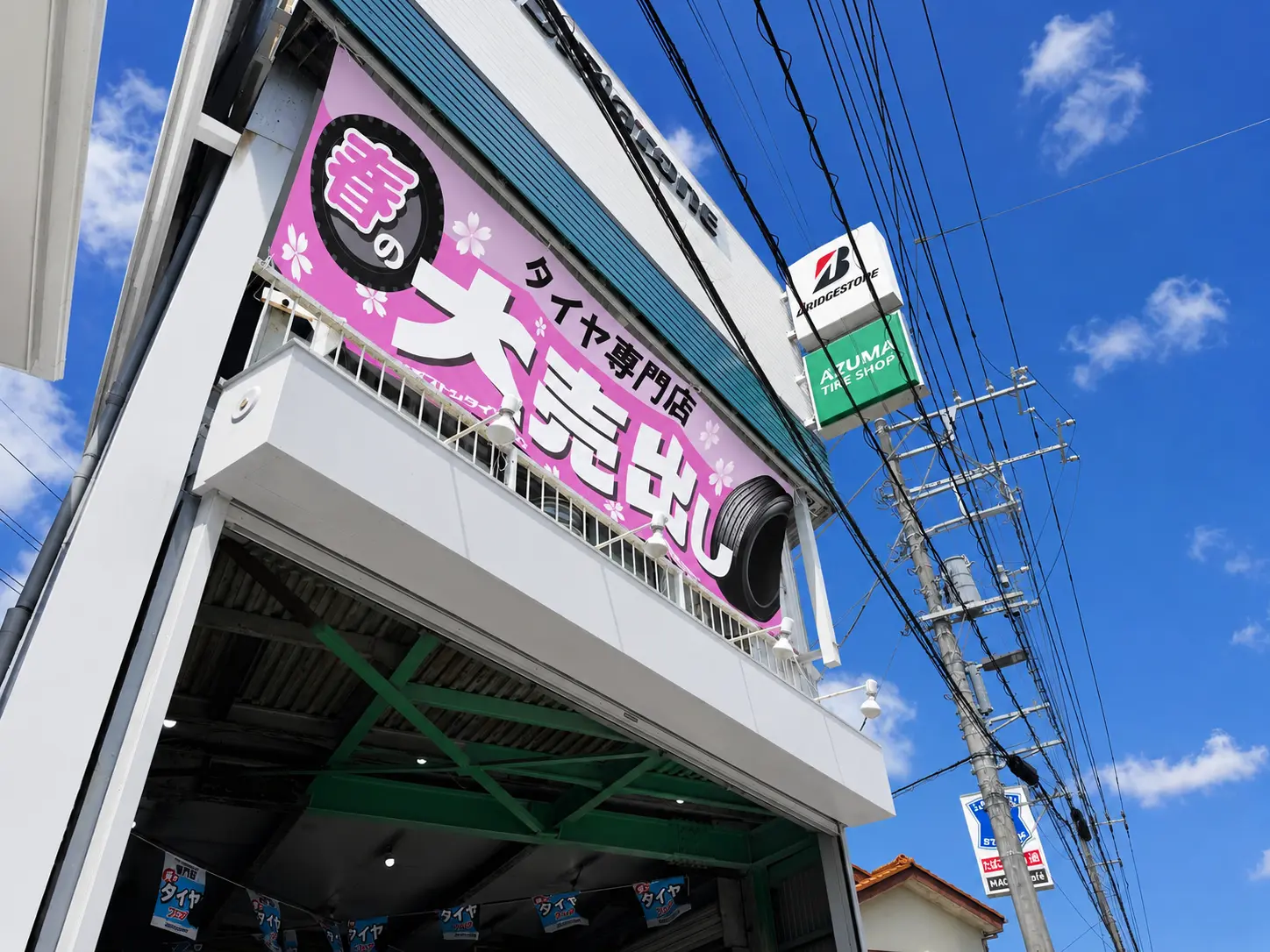 青空の下に建つ有限会社東タイヤ商会の店舗とブリヂストンの看板